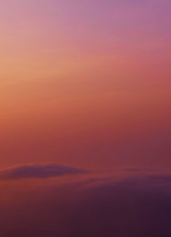 Soft orange and pink sunset sky with hazy clouds near the horizon.