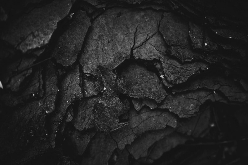 Chipped, jagged dark rocks with rough, cracked textures and subtle highlights scattered across the surface