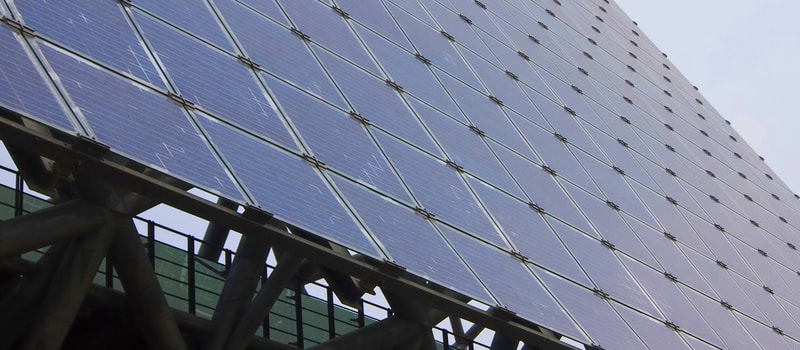 Solar panels arranged in a large angled array mounted on a steel framework of a building.