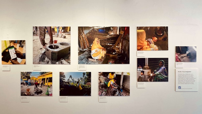 A gallery wall displays a grid of documentary photos showing people working in scenes of daily life, with small captions beneath each image.
