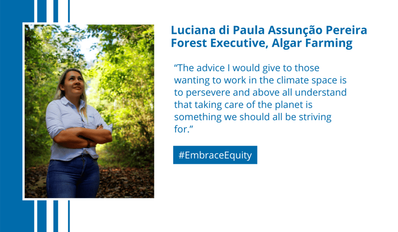 Luciana di Paula Assunção Pereira standing in a forest with arms crossed, wearing a light shirt and jeans, sunlit greenery in the background. #EmbraceEquity text on the right.