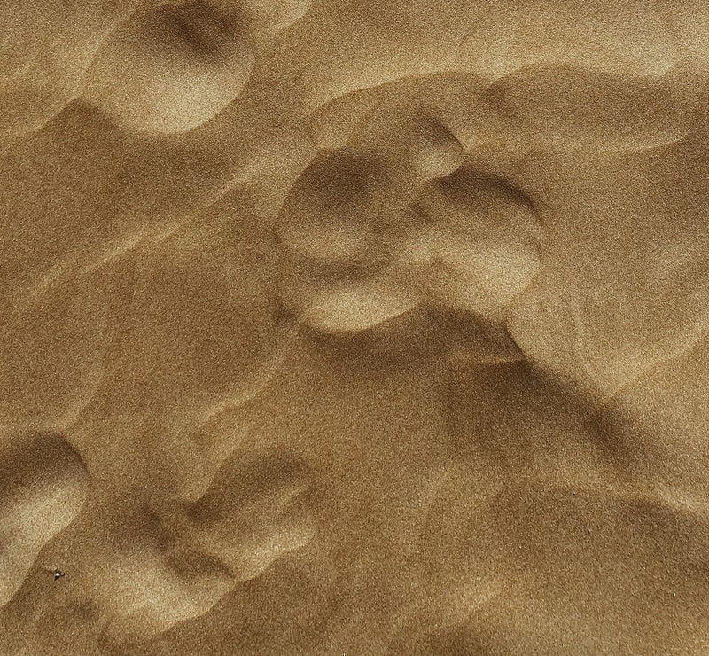 granulated desert sand with small, rounded dunes and subtle shadows across the landscape