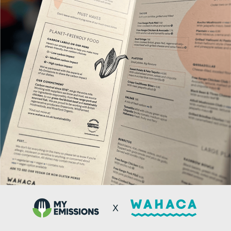 Open menu pages with planet-friendly section and doodle of corn, plus bottom branding logos for My Emissions and Wahaca.