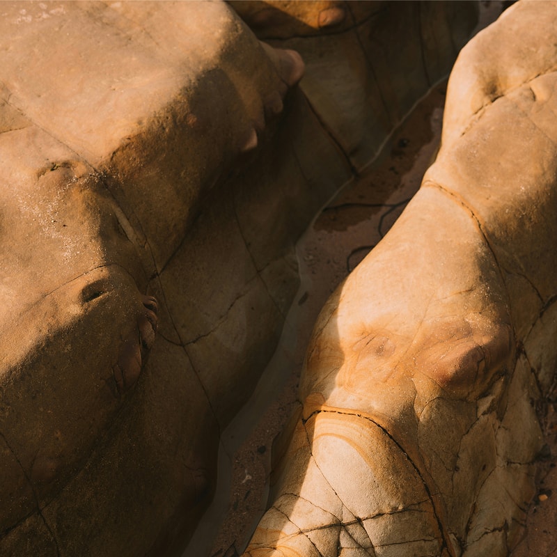 Smooth, weathered orange-brown rocks with cracks and crevices forming a narrow crevice.