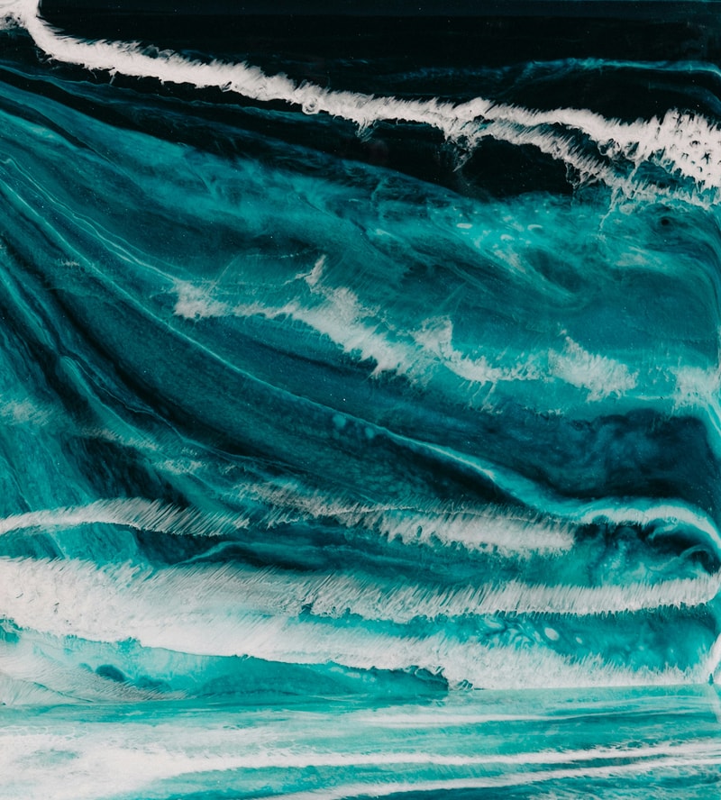 vibrant teal and turquoise abstract waves with white foamy accents and dark blue-black shading, resembling layered ocean currents and shoreline patterns