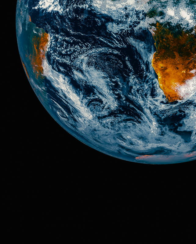 Viewed from space, the Earth’s edge dominates the frame with swirling blue oceans and white clouds, while parts of Africa and surrounding regions appear in warm brown and orange tones against the black of space.